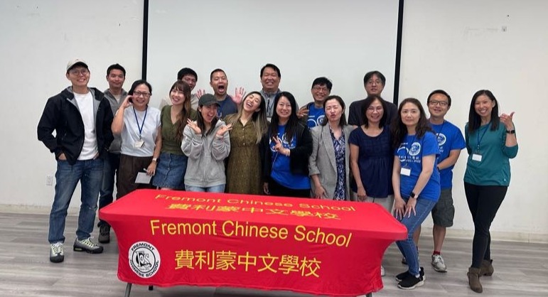FCS parent volunteers and staff standing together behind a Fremont Chinese School banner.